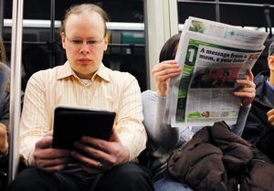 A commuter (L) reads on a Kindle e-reader while riding the subway in Cambridge, Massachusetts. Image by: BRIAN SNYDER